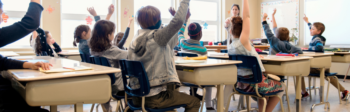 Students sit in class with arms raised