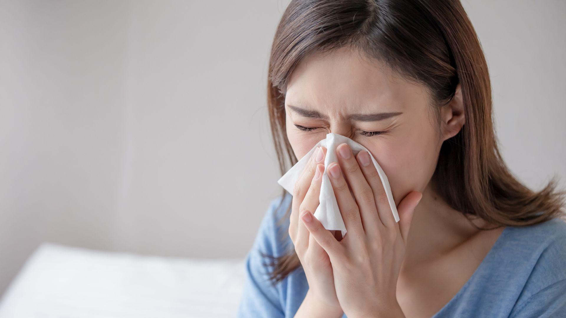 Woman sneezing into handkerchief