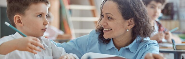 Teacher helps student in clean classroom—HVAC air filters ensure healthy school air.