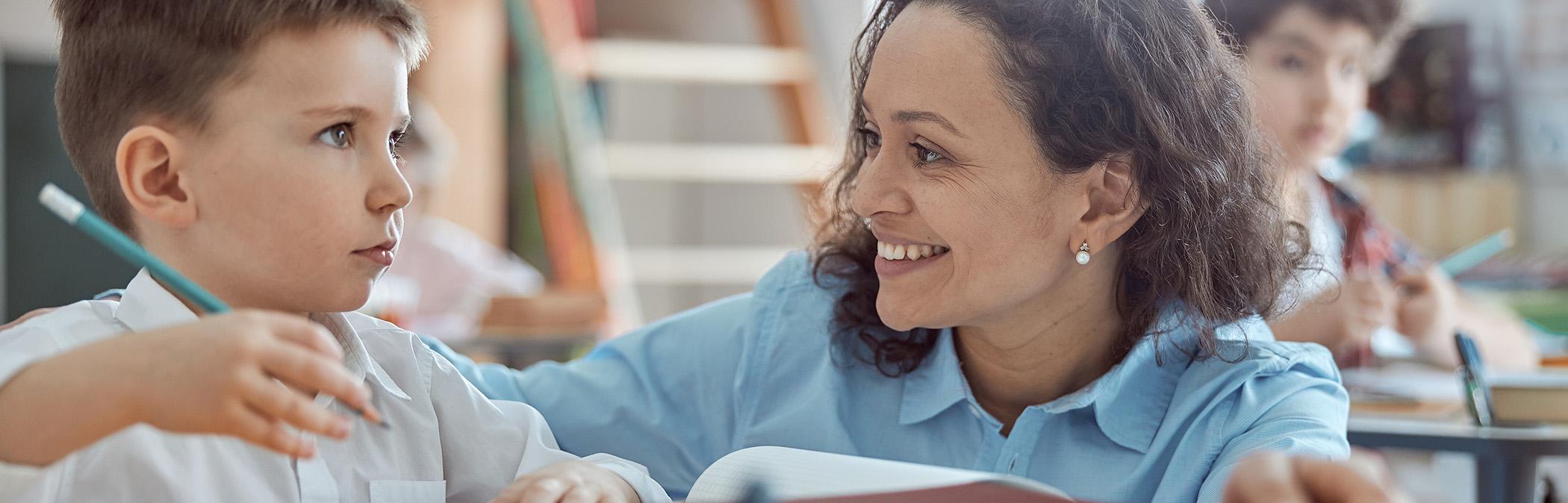 Teacher helps student in clean classroom—HVAC air filters ensure healthy school air.